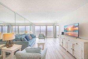 Relax in this spacious living room with ocean views, featuring a comfortable seating area with a sofa, armchairs, and TV.