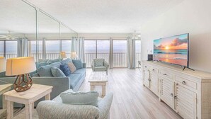 A spacious living room with a large TV, comfortable seating, and a balcony with a view. - Stunning View- Low Density Complex (Gulf Shores)