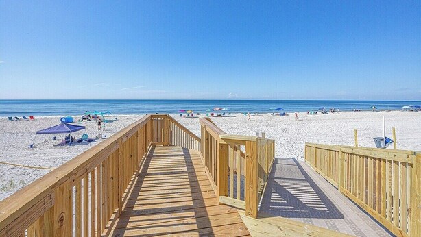 A wooden boardwalk leading to a beach with umbrellas and beach chairs. - Stunning View- Low Density Complex (Gulf Shores)