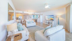 A spacious living area with a ceiling fan, a dining area, and a kitchen in the background.