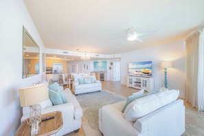 A spacious living area with a ceiling fan, a dining area, and a kitchen in the background.
