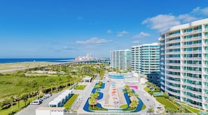 A hotel with a pool, a beach view, and a parking area.
