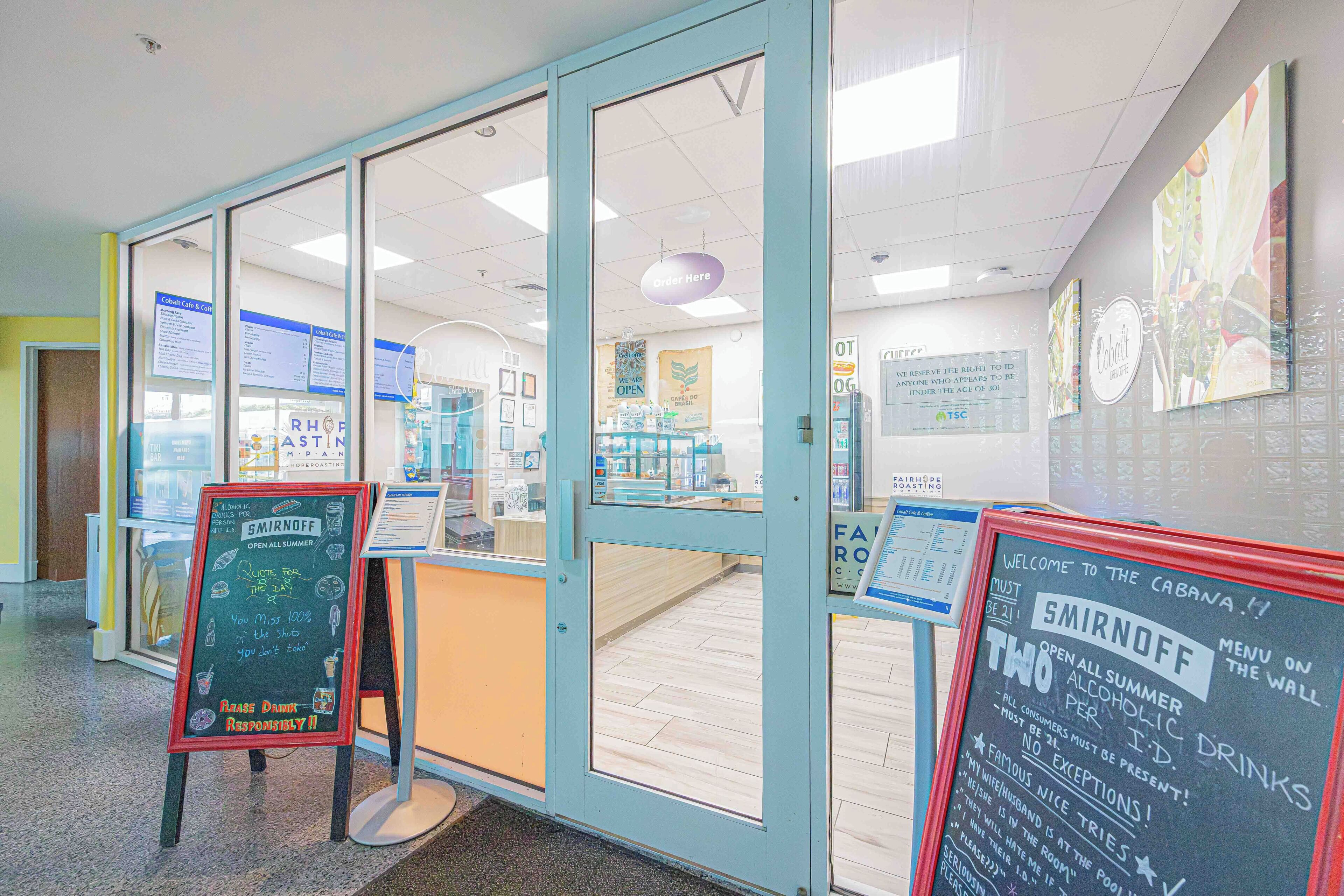 A room with a glass door, a chalkboard menu, and informational posters on the walls.