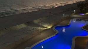 Ein Schwimmbecken mit Sonnenuntergangsblick, eine Flagge und ein Sandstrand.