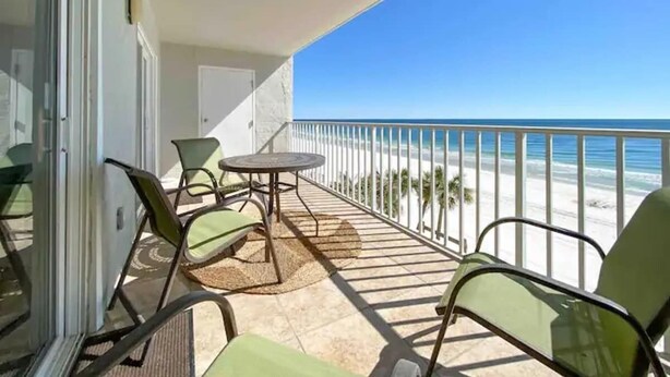 Ein Balkon mit Blick auf den Strand, ausgestattet mit Stühlen und einem Tisch.