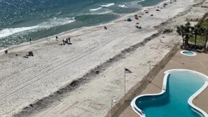 Ein Strand mit Poolbereich, darunter ein Pool mit ungewöhnlicher Form und eine Fahnenstange.