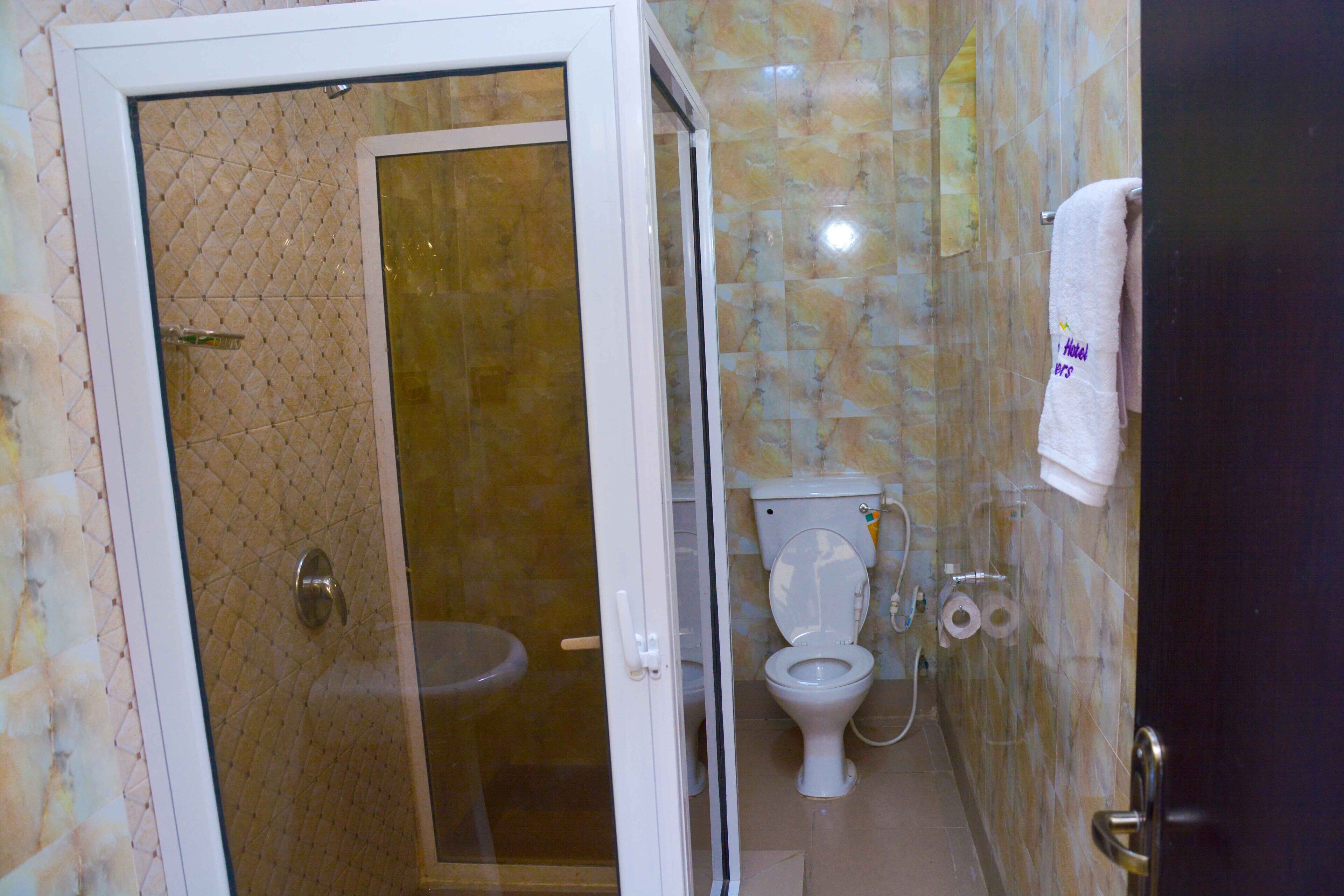 A bathroom with a glass-enclosed shower, a toilet, and a towel hanging on the wall.