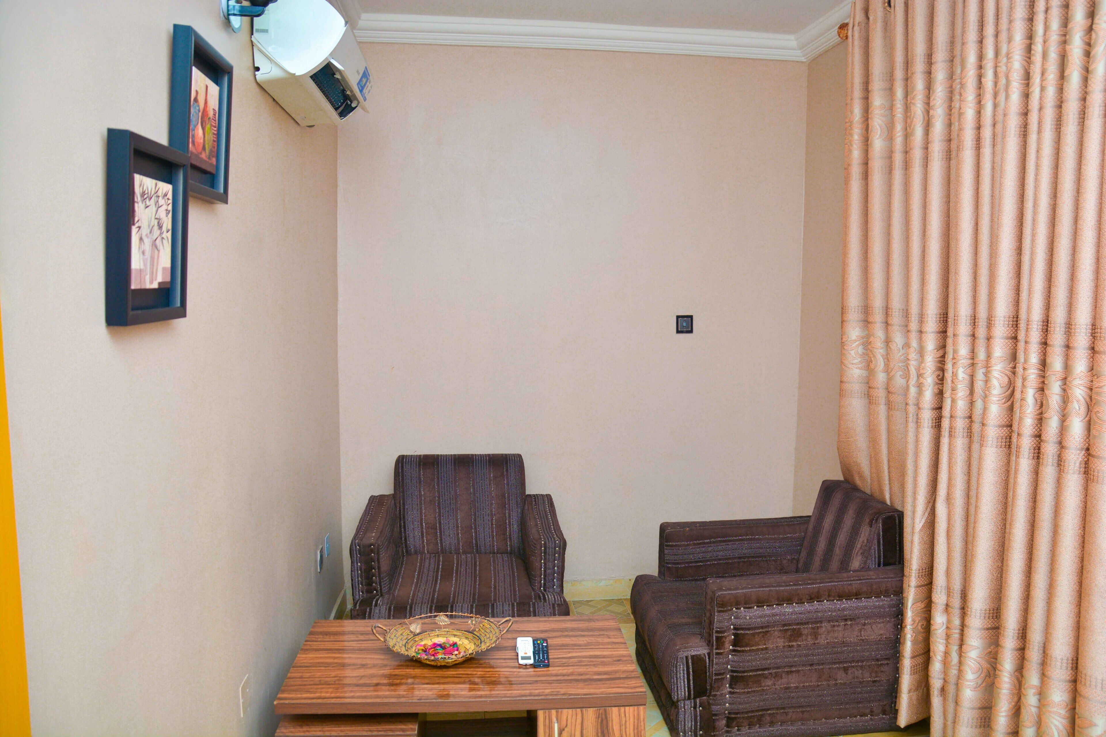 Ein Zimmer mit zwei Sofas, einem kleinen Tisch mit einer Schüssel und einer Fernbedienung sowie gerahmten Bildern an der Wand.