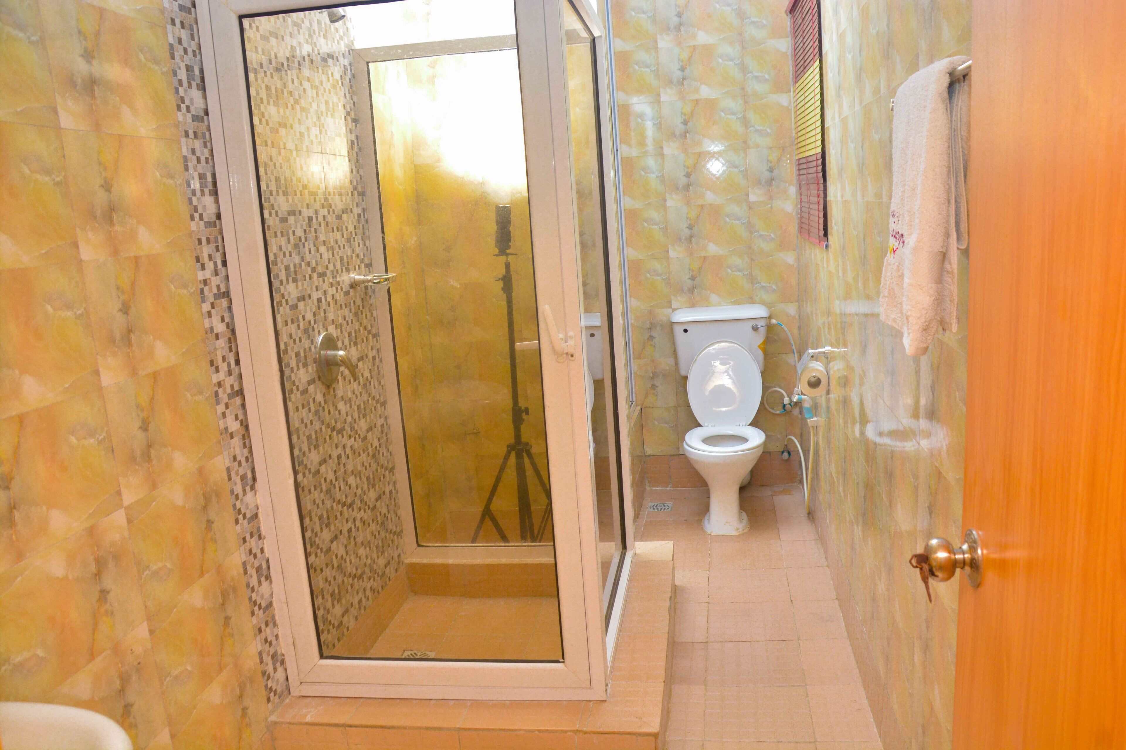 A bathroom with a shower enclosure, toilet, and a towel hanging on the wall.