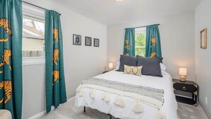 Une chambre à coucher avec un lit, des rideaux, des lampes de chevet et une fenêtre.