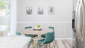Une cuisine moderne avec une table à manger ronde, des chaises vertes et un réfrigérateur en acier inoxydable.