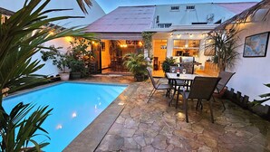 A poolside area with a stone patio, outdoor seating, and a barbecue grill.