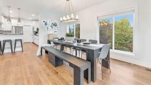 Una cocina moderna con una isla central, iluminación colgante y ventanas amplias con vistas al exterior.