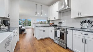 Una cocina moderna con armarios blancos, electrodomésticos de acero inoxidable y suelo de madera.