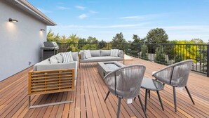 Una terraza con sofá, sillas y una parrilla.