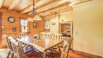 Une salle à manger rustique avec une table et des chaises en bois, un lustre et des murs en bois.
