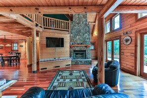Ein Blockhaus-Interieur mit Kamin aus Stein, Holzmöbeln und einem Balkon.