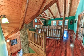 Ein Innenraum aus Holz mit einer Steinsäule, einer Holztreppe und einem Geländer.