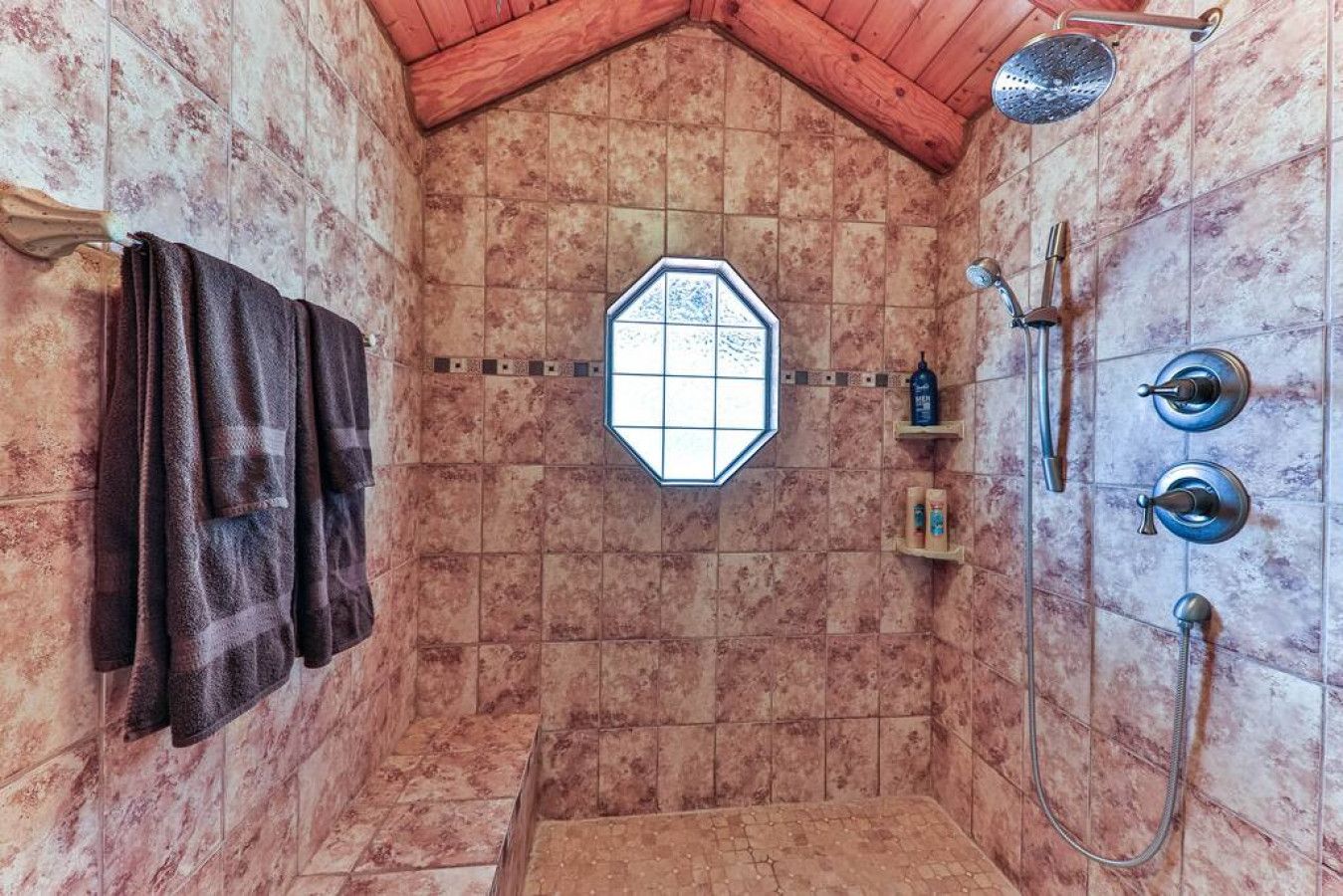 A shower room with a sloped ceiling, a window, and a towel rack.