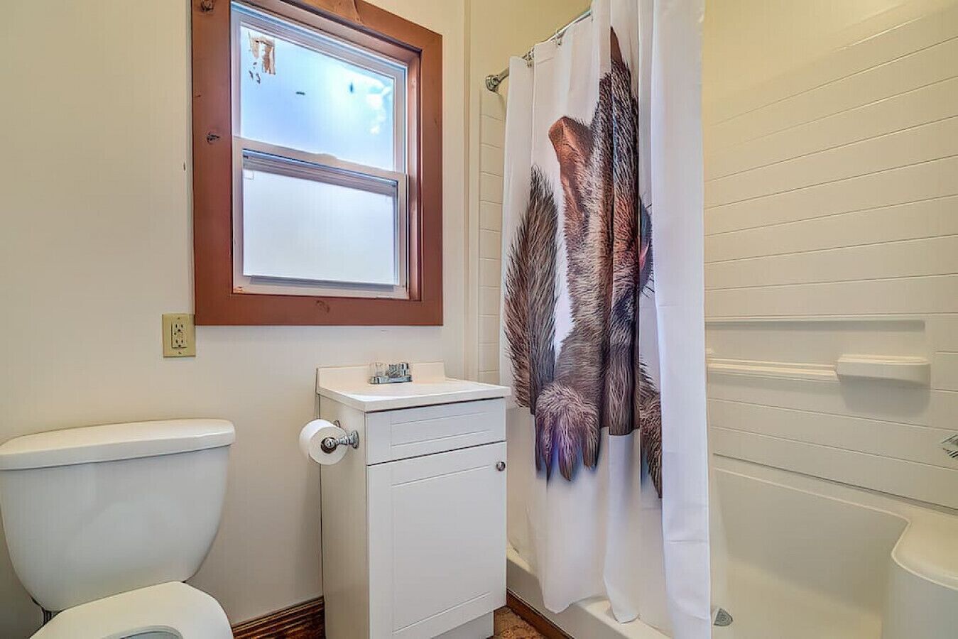 A bathroom with a toilet, a window, and a shower curtain.