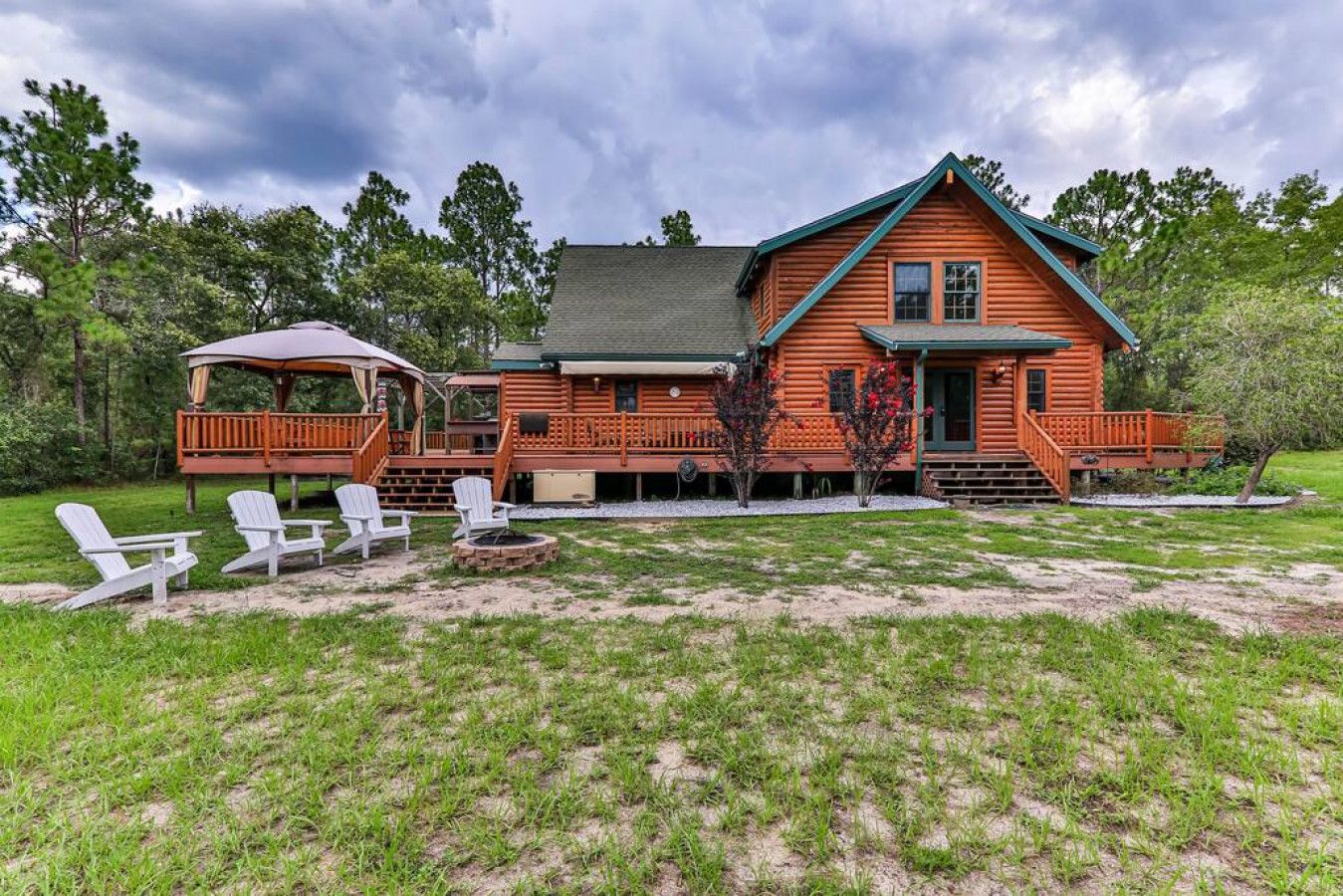 A log cabin with a deck, outdoor seating, and a fire pit.