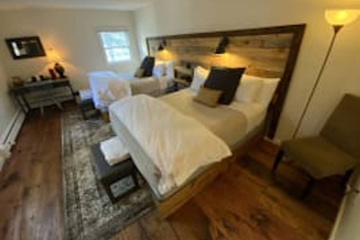A bedroom with a large bed, bedside tables, a chair, and a lamp.
