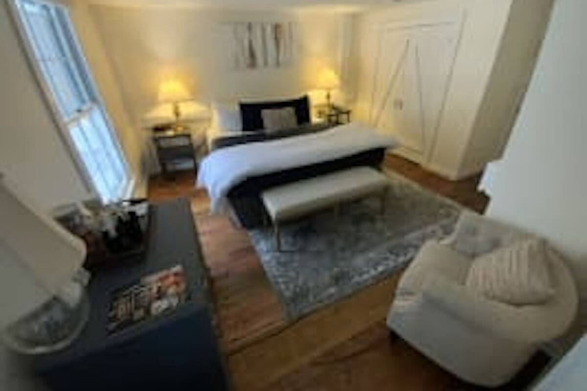 A bedroom with a bed, bedside tables, a desk, and a chair.