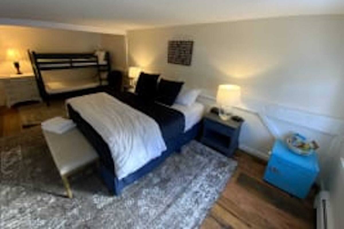 A bedroom with a bunk bed, bedside tables, a lamp, and a small blue cabinet.