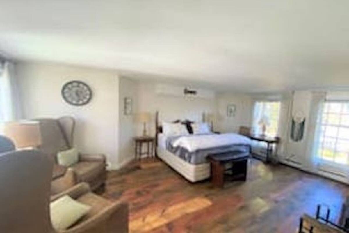 A bedroom with a bed, a chair, a small table, and a window.
