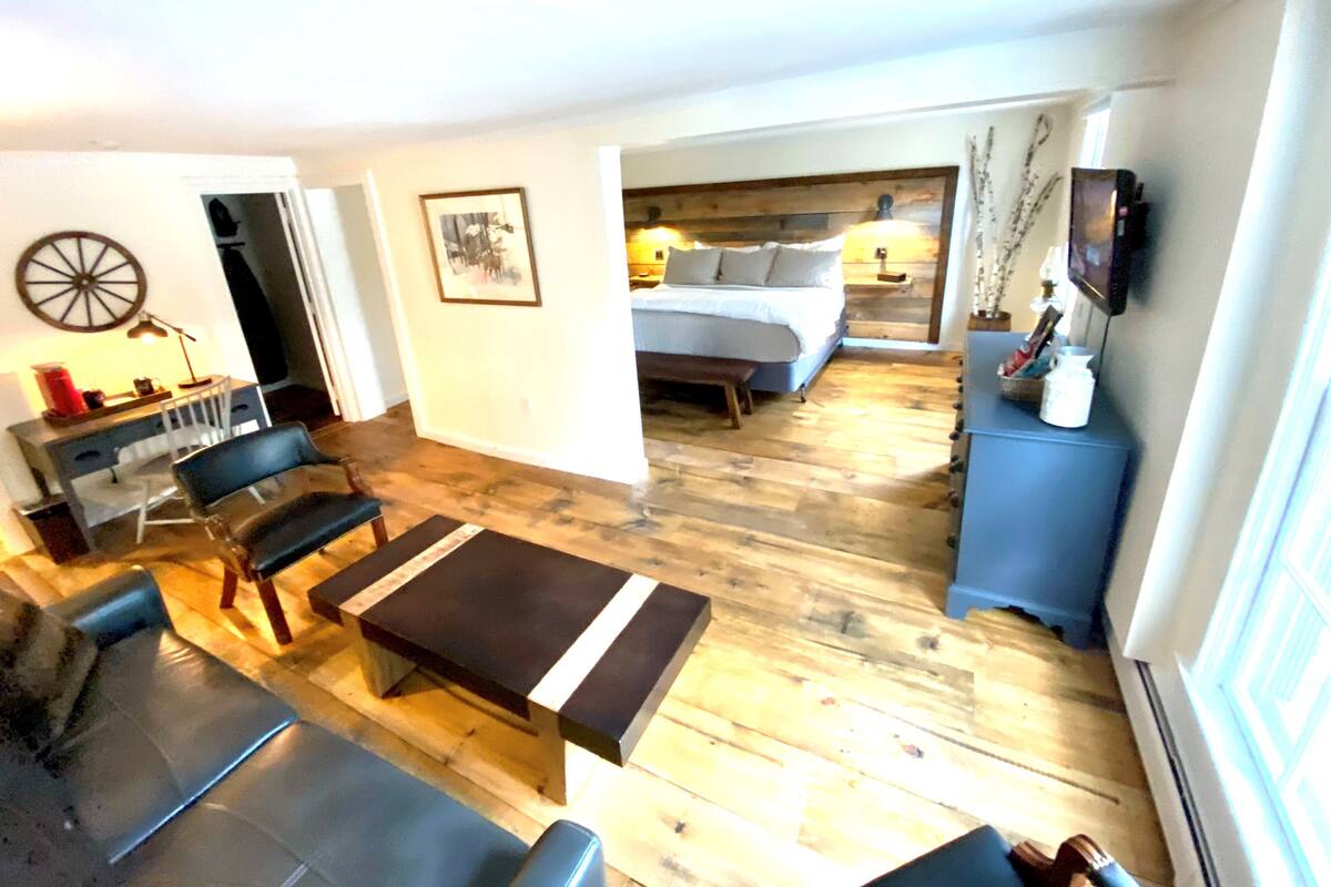 A compact room with a bed, a desk, and a seating area.