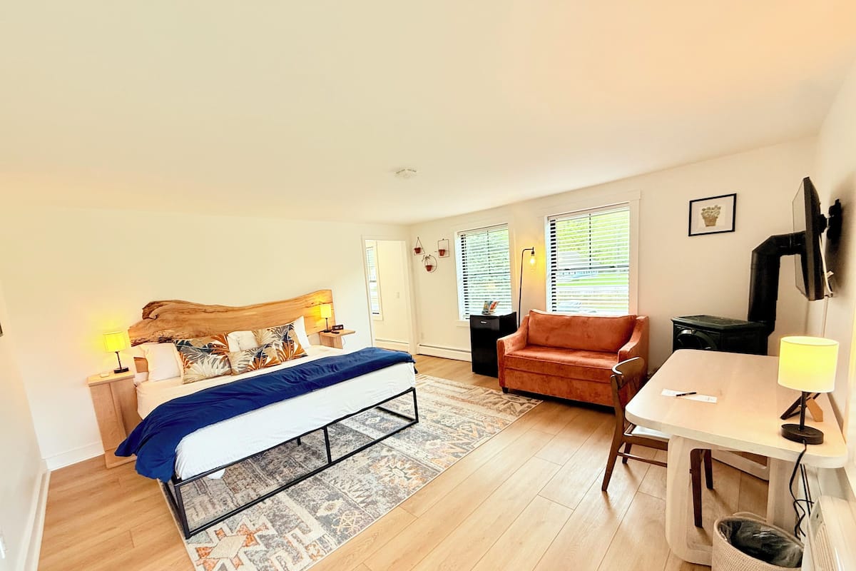 A bedroom with a bed, a desk, a chair, and a sofa.