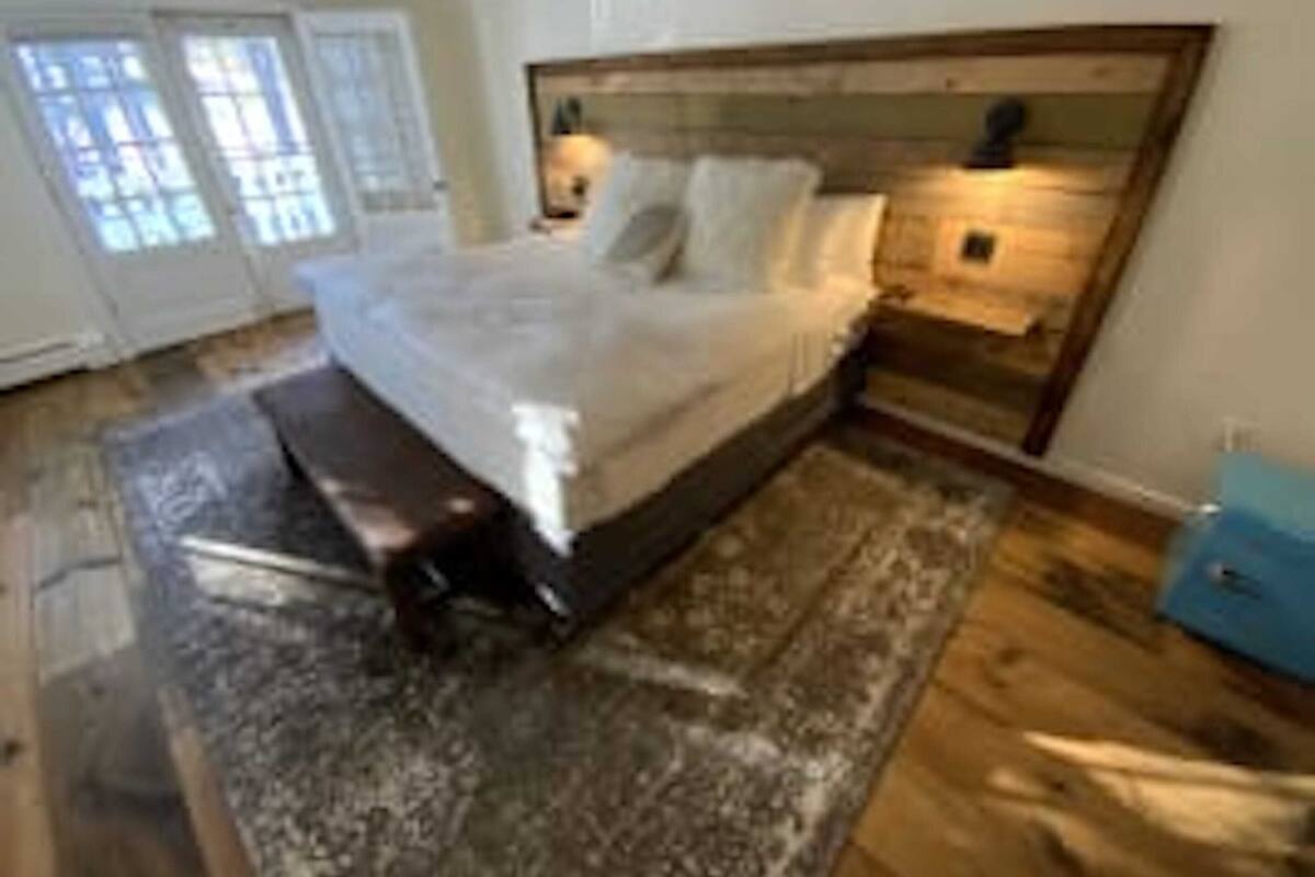 A bedroom with a large bed, a wooden headboard, a bench, a nightstand, and a blue cabinet.