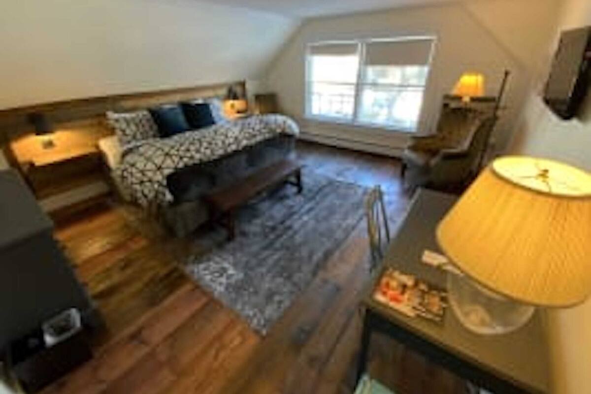 A bedroom with a bed, bedside tables, a desk, and a lamp.