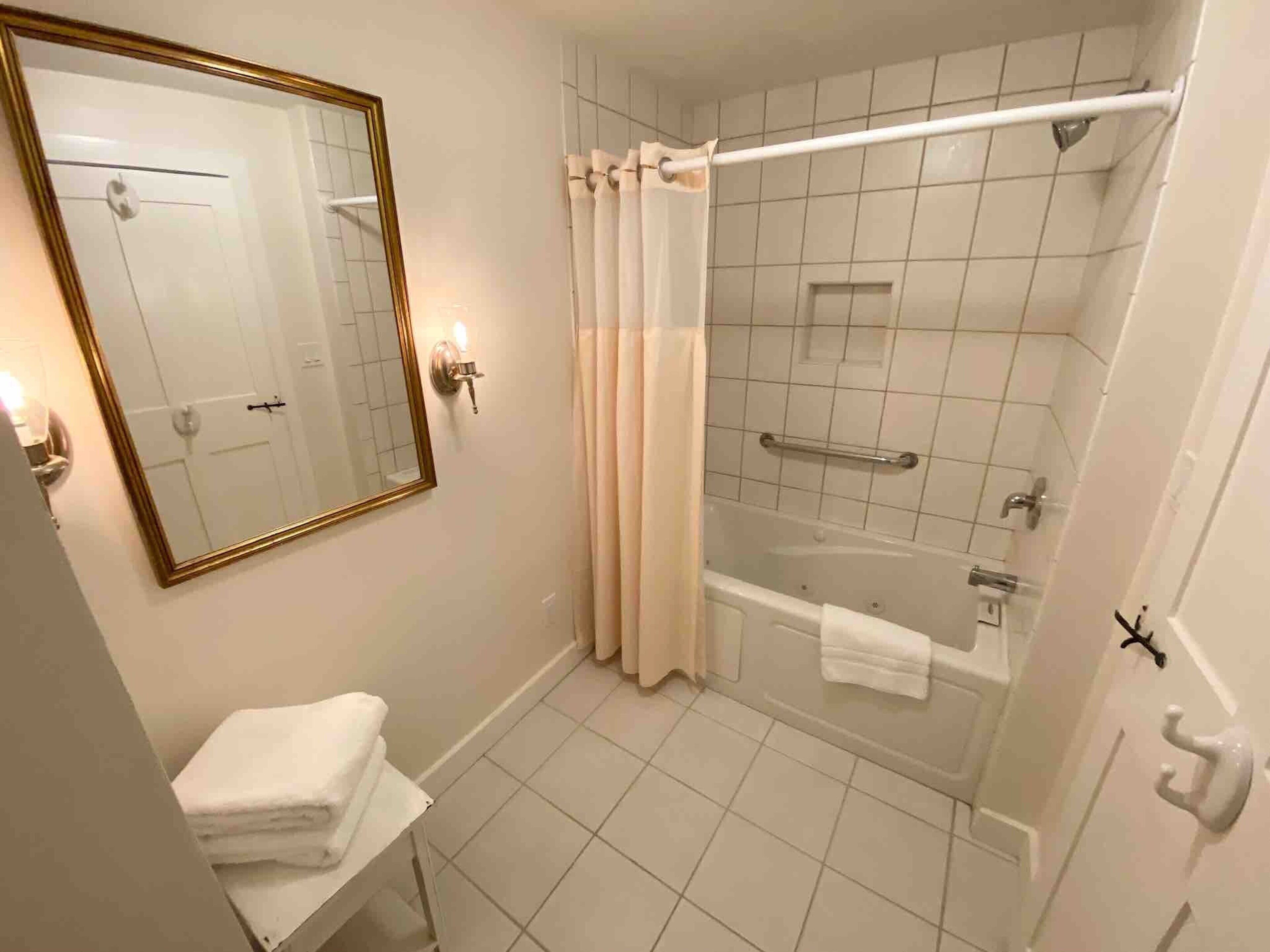 A bathroom with a bathtub, a shower, a sink, a mirror, and a towel rack.