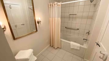 A bathroom with a bathtub, a shower, a sink, a mirror, and a towel rack.