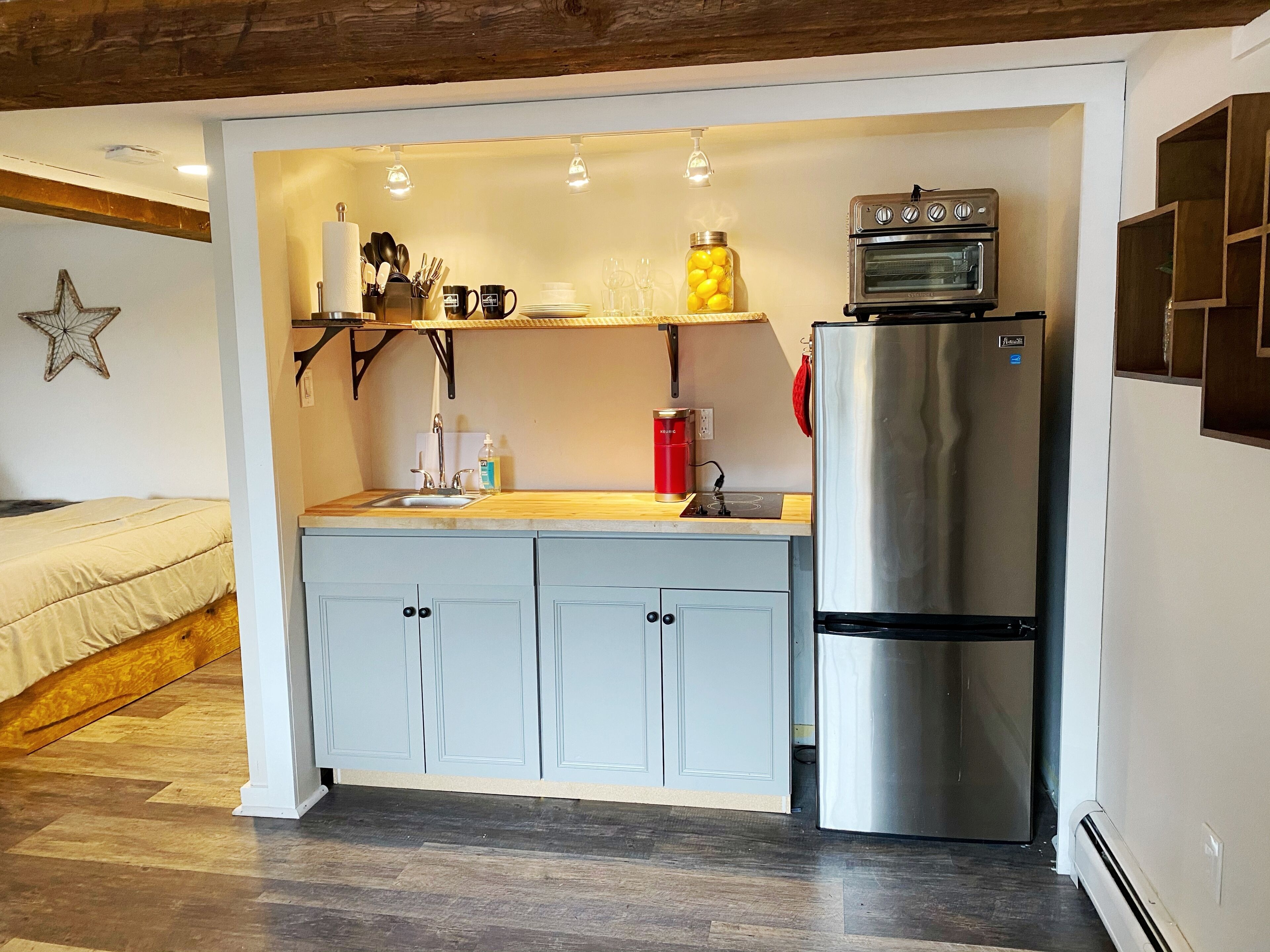 Cocina compacta con horno integrado, refrigerador y encimera de madera.
