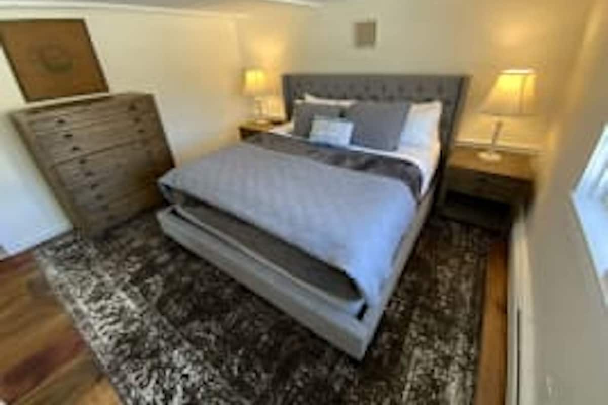 A bedroom with a bed, a dresser, and two bedside lamps.