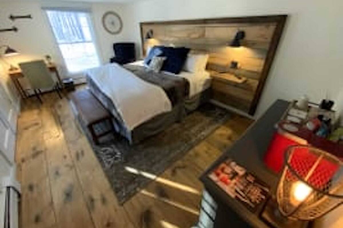A bedroom with a bed, bedside tables, a desk, and a chair.