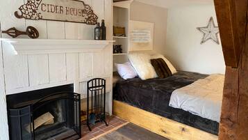 Um quarto acolhedor com lareira, uma cama com cabeceira e um letreiro que diz 'CIDER HOUSE'.