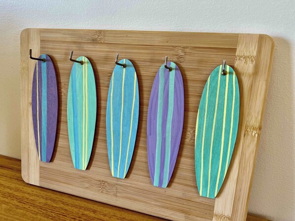 Een houten plank met vijf gestreepte stukken stof die aan haken hangen.