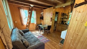 A wooden cabin interior with a sofa, dining table, chairs, and a kitchen area. - White Oak Tree House by Garden of the Gods in the Shawnee National Forest (Elizabethtown)