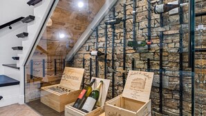 A wine cellar with wooden crates labeled 'Quintessa' and 'Nickel & Nickel' containing bottles. - NEW! Drift Inn-Lakefront Home w/ Hot Tub, Outdoor Bar, Golf! (Lake Worth)