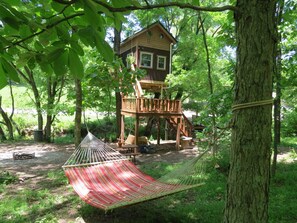 A treehouse with a wooden deck and a hammock.