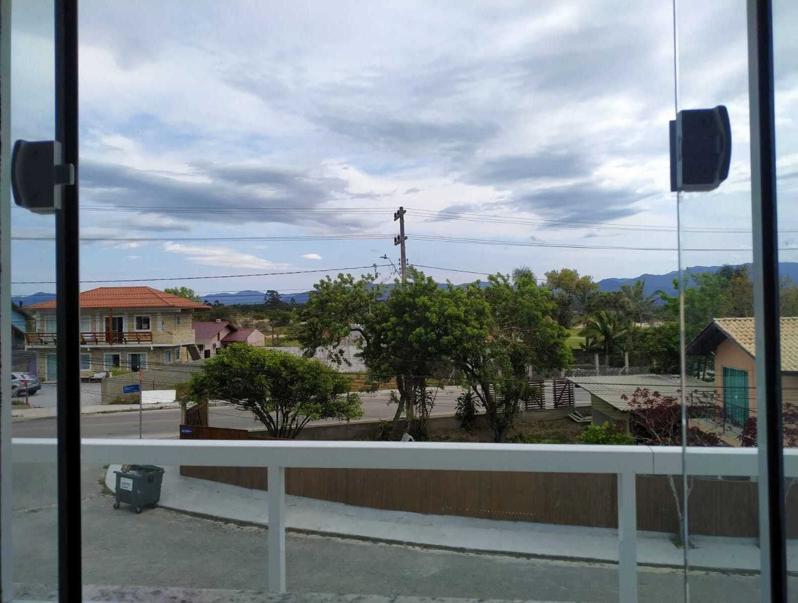 A view from a window overlooking a street with buildings, trees, and mountains in the background.