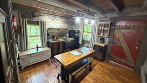 Une cuisine rustique avec des meubles de rangement en bois, une table à manger en bois et une porte de style grange rouge.