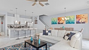 A modern living room with a white sofa, a coffee table, and a patterned rug. - 5129 Compass Bay 8 guests 4DBR BBQ near Disney (Kissimmee)
