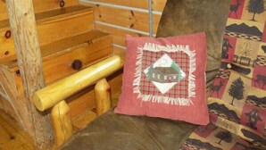 A wooden staircase with a handrail, a cushioned bench with a decorative pillow, and a window with a view of trees. - The Hickory Hollow Log Cabin by Garden of Gods in the Shawnee National Forest (Elizabethtown)