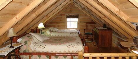 A cozy attic bedroom with a wooden bed, a nightstand, a lamp, and a rocking chair.