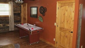 A room with a pool table, wooden walls, a ceiling fan, and a door. - The Pine Ridge Home by Garden of the Gods in the Shawnee National Forest (Herod)