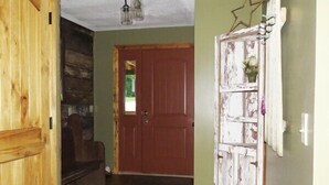 A wooden door, a hallway with a wooden floor, a red door, and a wall with a decorative piece. - The Pine Ridge Home by Garden of the Gods in the Shawnee National Forest (Herod)